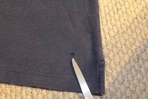 Navy blue polo with a hole near the hem.