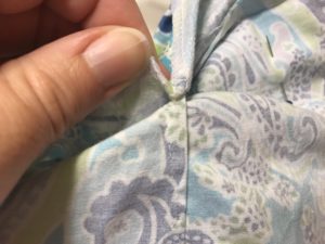 Undo the stitching tacking the facing down.